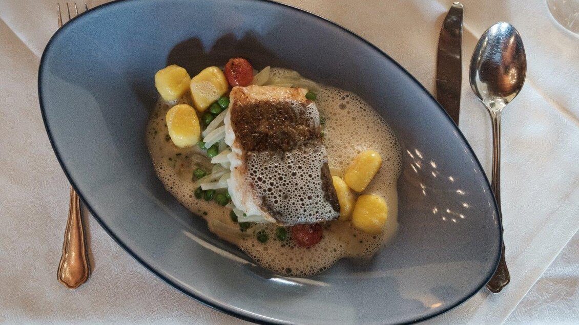 Ein kunstvoll angerichteter Fisch auf einem Bett aus Gemüse und Gnocchi. Dazu eine cremige Sauce und frische Tomaten. | © Schilcherland Steiermark