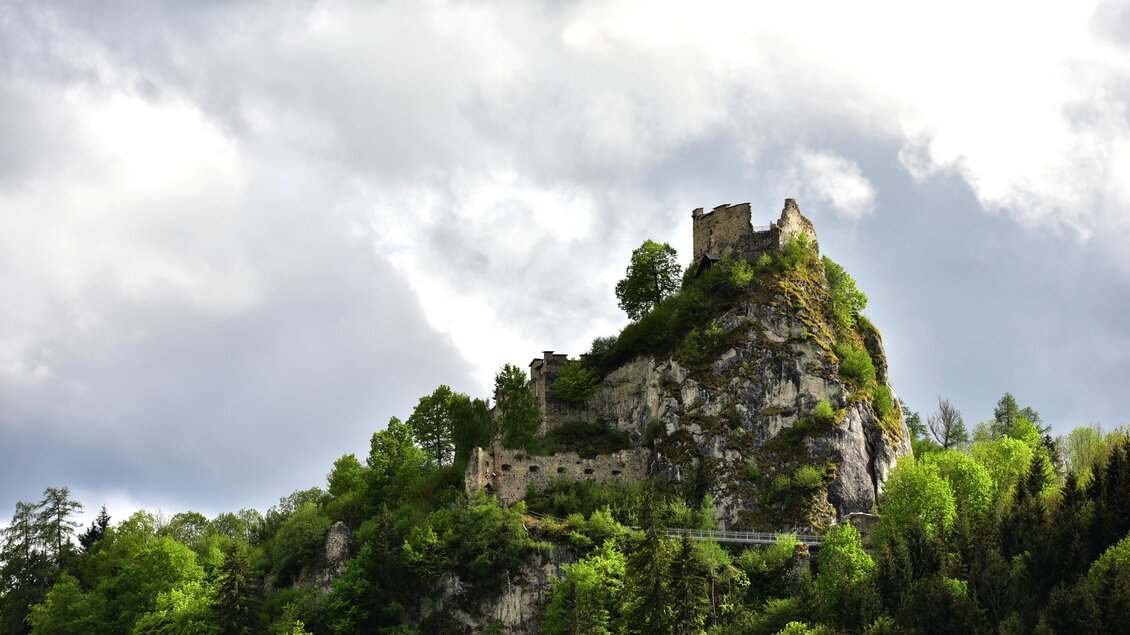 Eine alte Burg steht auf einem Hügel, umgeben von grünen Bäumen. Der Himmel ist bewölkt, was eine mystische Atmosphäre schafft. | © Erlebnisregion Murtal