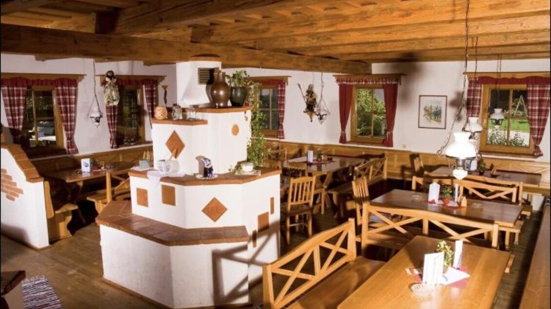 Ein gemütliches Restaurant mit Holzmöbel und rustikaler Einrichtung. Große Fenster bieten einen Blick auf die Natur draußen. | © Weingut Kleinschuster