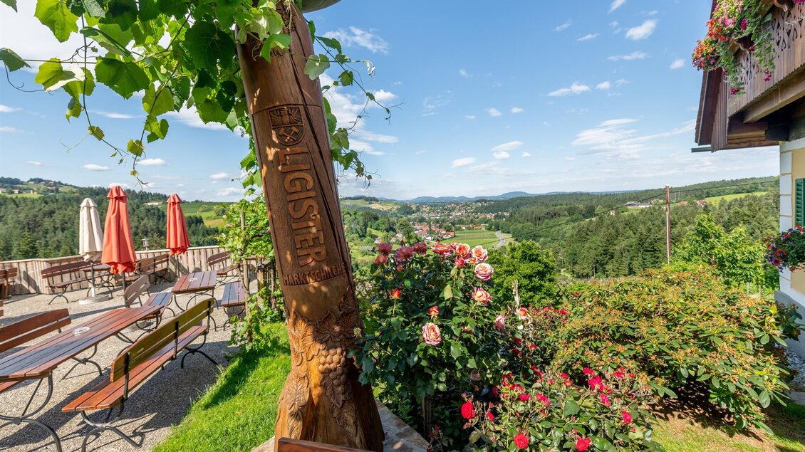 Eine malerische Landschaft mit einer Terrasse, auf der stehen Stühle und Tische. Bunte Blumen und ein klarer blauer Himmel ergänzen die idyllische Aussicht. | © Die Abbilderei