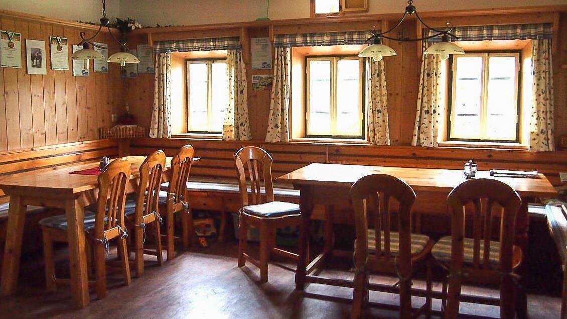 Ein gemütlicher Raum mit Holzmöbeln und großen Fenstern. Die Wände sind mit Holz verkleidet, und die Atmosphäre ist einladend und warm. | © Buschenschank Eckfastl