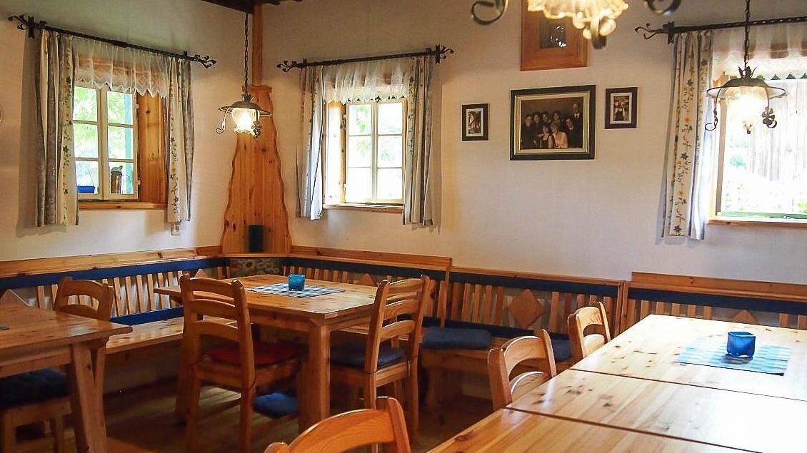 Ein gemütlicher Gastraum mit Holzmöbeln und großen Fenstern. Der Raum ist freundlich und einladend, ideal für gesellige Zusammenkünfte. | © Buschenschank Eckfastl