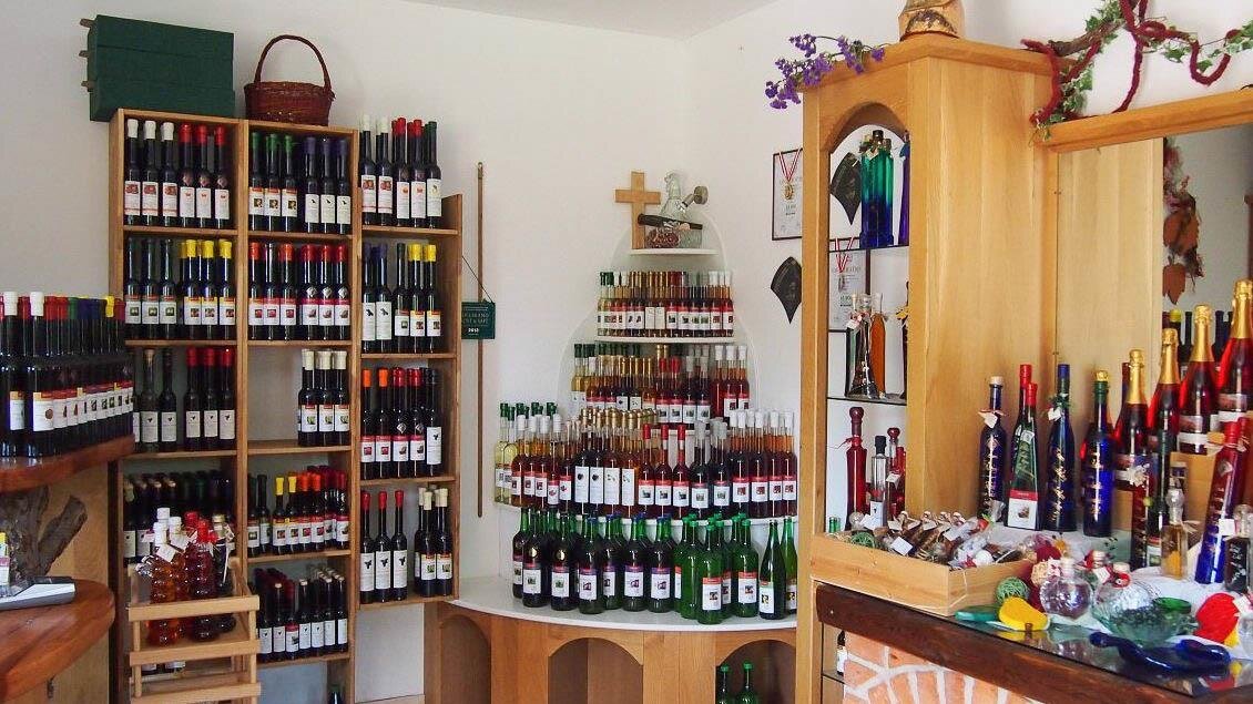 Ein gut sortierter Weinausschank mit vielen Flaschen Wein und Likör. Das Interieur ist aus Holz und wirkt einladend. | © Buschenschank Eckfastl