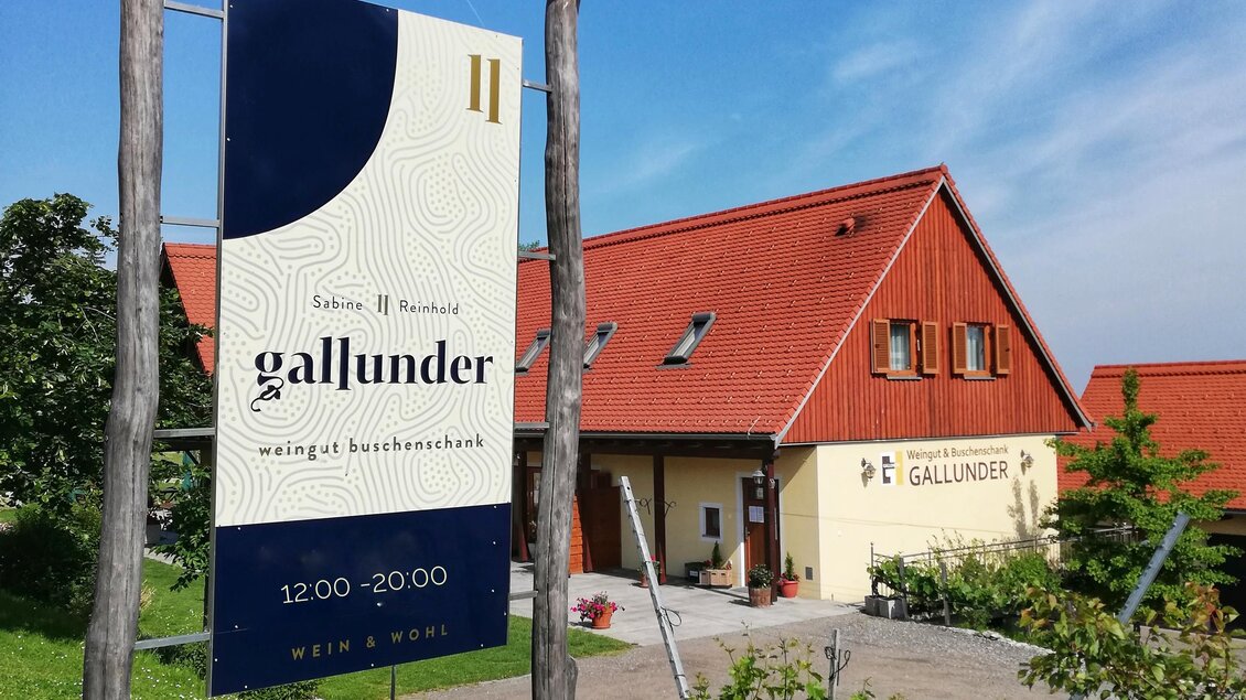 Ein modernes weißes und rotes Gebäude mit einem Schild, das "gallunder" anzeigt. Der Himmel ist blau und der Garten ist grün gestaltet. | © Sabine Gallunder