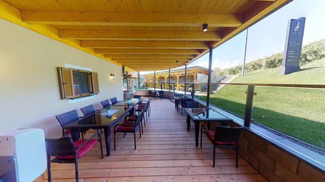 Eine einladende Terrasse mit Holzboden und Tischen. Im Hintergrund grünes Gras und eine klare Aussicht. | © Buschenschank Pichlippi