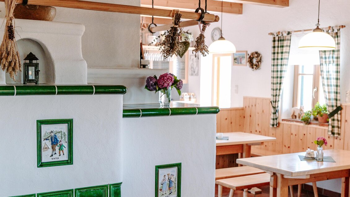 Ein gemütliches Restaurant mit Holzdecke und weißen Wänden. Die grüne Fliese und die einfachen Tische schaffen eine einladende Atmosphäre. | © Familie Hartinger