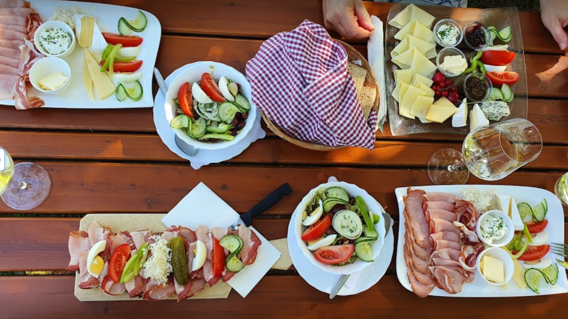 Ein üppiges Picknick mit verschiedenen Käsesorten, Aufschnitt und frischen Salaten. Die Tische sind mit köstlichen Speisen und Getränken gedeckt. | © Weingut Hopfer
