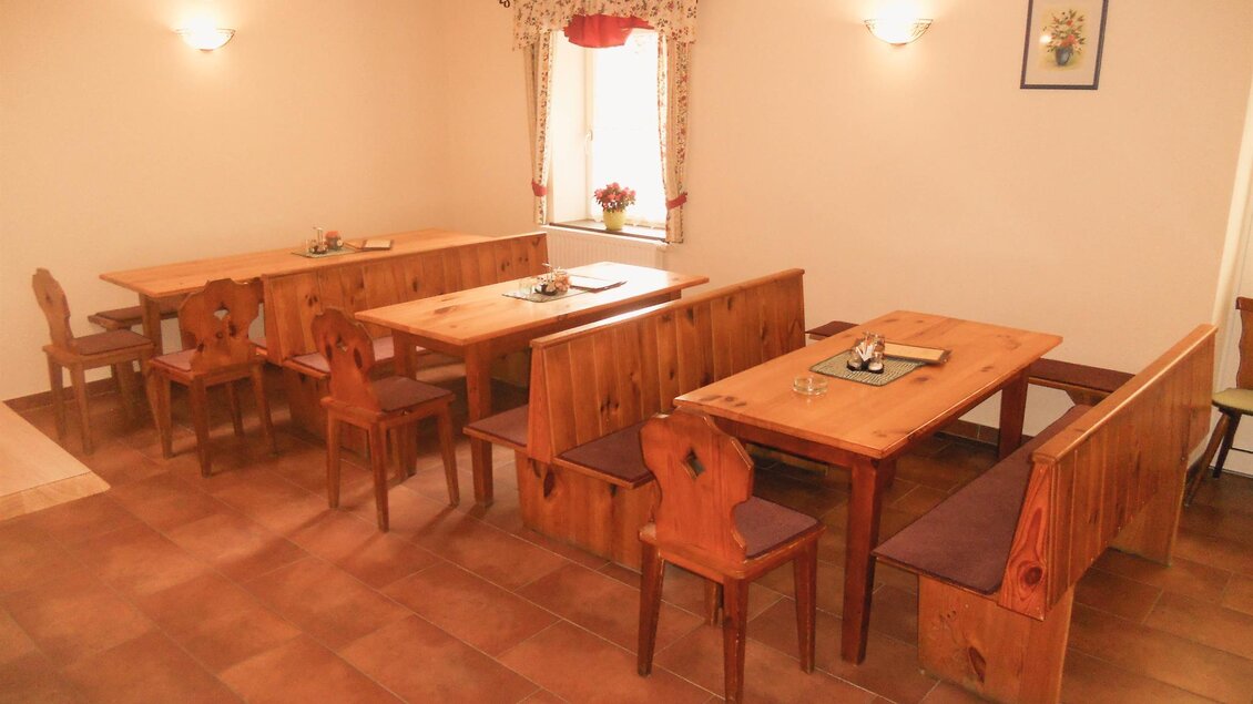 Ein gemütlicher Raum mit Holztischen und Bänken. Sanfte Beleuchtung und warme Farben schaffen eine einladende Atmosphäre. | © Lederer