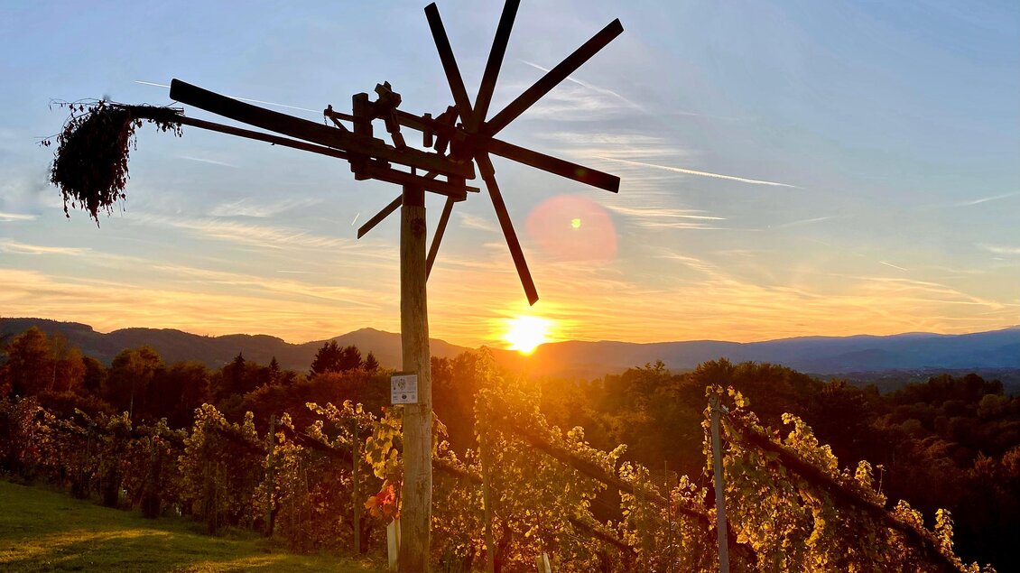 Ein wunderschönen Sonnenuntergang über Weinbergen mit einem alten Weinfass. Die Silhouette des Weinfass ist vor dem farbenfrohen Himmel zu sehen. | © Klapotetzhof Silberschneider