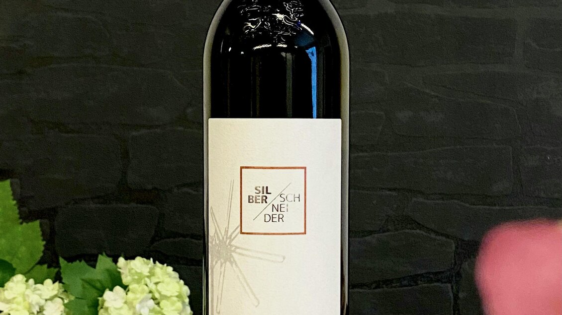 Eine Flasche Sauvignon Blanc steht auf einem runden Untersetzer. Im Hintergrund sind dekorative Pflanzen zu sehen.