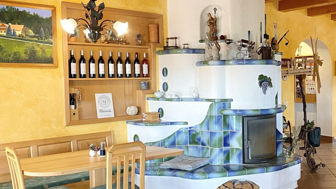 Ein einladendes Restaurant mit Holzdekor und einer warmen Farbgestaltung. Im Hintergrund sind Weinflaschen in einem Regal und ein Kamin zu sehen.