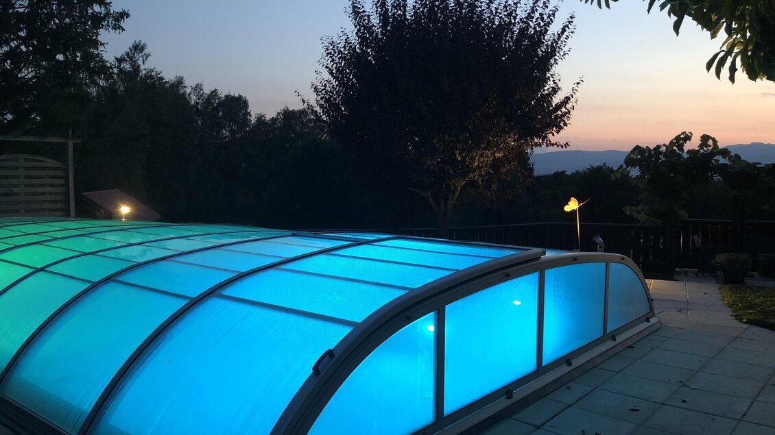 Ein Schwimmbad mit einer blauen Überdachung bei Sonnenuntergang. Die Umgebung ist ruhig und von Bäumen umgeben. | © Brigitte Maier | Klapotetzhof Silberschneider