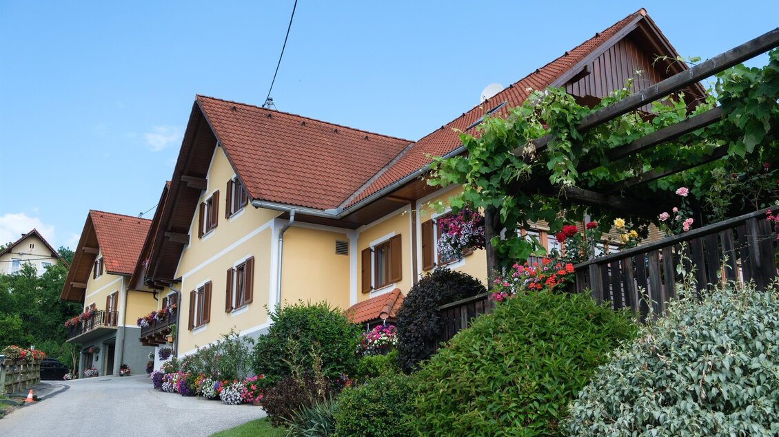 Ein charmantes Haus mit einem roten Satteldach und bunten Blumenkästen. Der gepflegte Garten und die ruhige Umgebung verleihen der Szene eine einladende Atmosphäre. | © Schilcherland Steiermark
