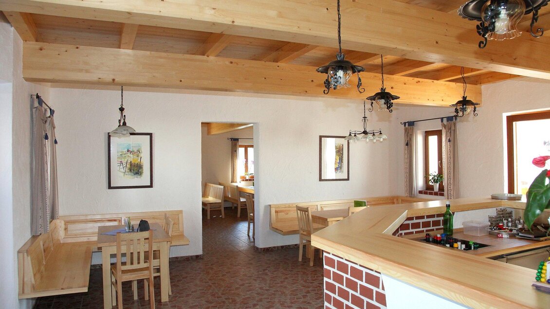 Ein einladendes Restaurant mit Holzdecken und warmem Licht. Die Einrichtung besteht aus einfachen Tischen und Bänken, ergänzt durch dekorative Bilder an den Wänden. | © Familie Kober