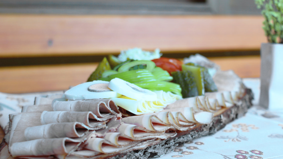 Ein schön angerichteter Teller mit Aufschnitt, Käse und frischem Gemüse. Die Farben sind appetitlich und der Teller steht auf einem hölzernen Tisch. | © Marion & Peter Labanz | Buschenschank Labanz