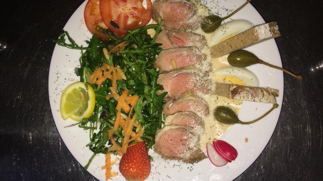 Ein Teller mit zartem Fleisch, umgeben von frischem Salat, Karotten und Tomatenscheiben. Garniert mit Zitronenscheibe und Kapern. | © Buschenschank Musterstubn l Nina & Armin Polz-Kiefer