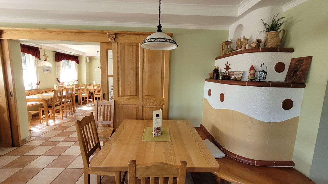 Ein gemütlicher Essbereich mit einem großen Holztisch und Stühlen. Im Hintergrund sind weitere Sitzplätze und dekorative Elemente an der Wand zu sehen. | © TV Südsteiermark - Irene Löschnig