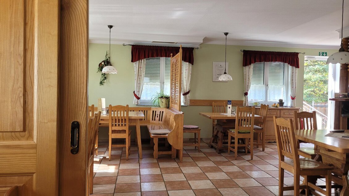 Ein gemütlicher Gastraum mit Holztischen und -stühlen. Große Fenster lassen viel Licht herein und die Atmosphäre wirkt einladend. | © TV Südsteiermark - Irene Löschnig