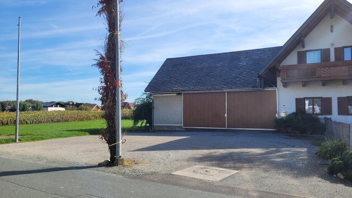 Ein ruhiges Wohngebiet mit einem modernen Haus und einem große Auffahrt. Im Hintergrund sieht man grüne Felder und einen blauen Himmel. | © TV Südsteiermark - Irene Löschnig