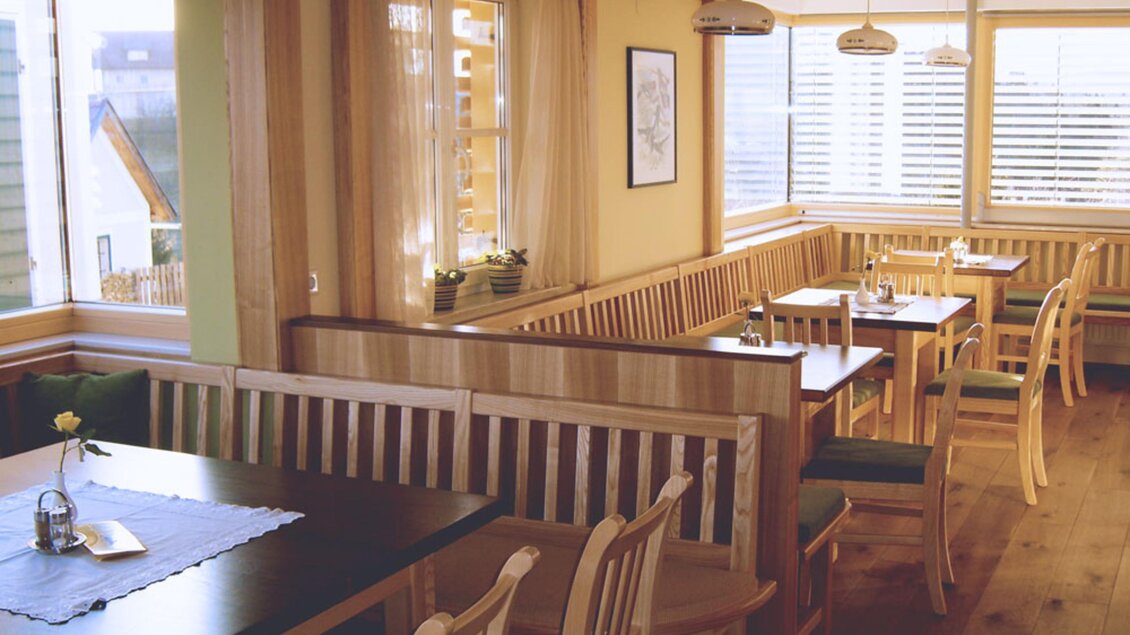 Ein gemütliches Restaurant mit Holzmöbeln und großen Fenstern. Die Tische sind sauber eingedeckt und es gibt eine einladende Atmosphäre. | © Familie Sternat | Weingut Sternat