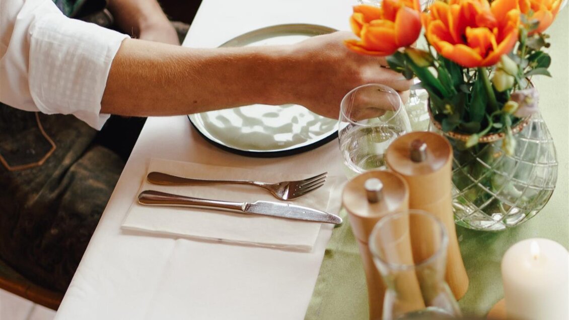 Ein schön gedeckter Tisch mit frischen Blumen und Gläsern. Im Vordergrund sind verschiedene Speisen und Getränke zu sehen. | © Tinnauer
