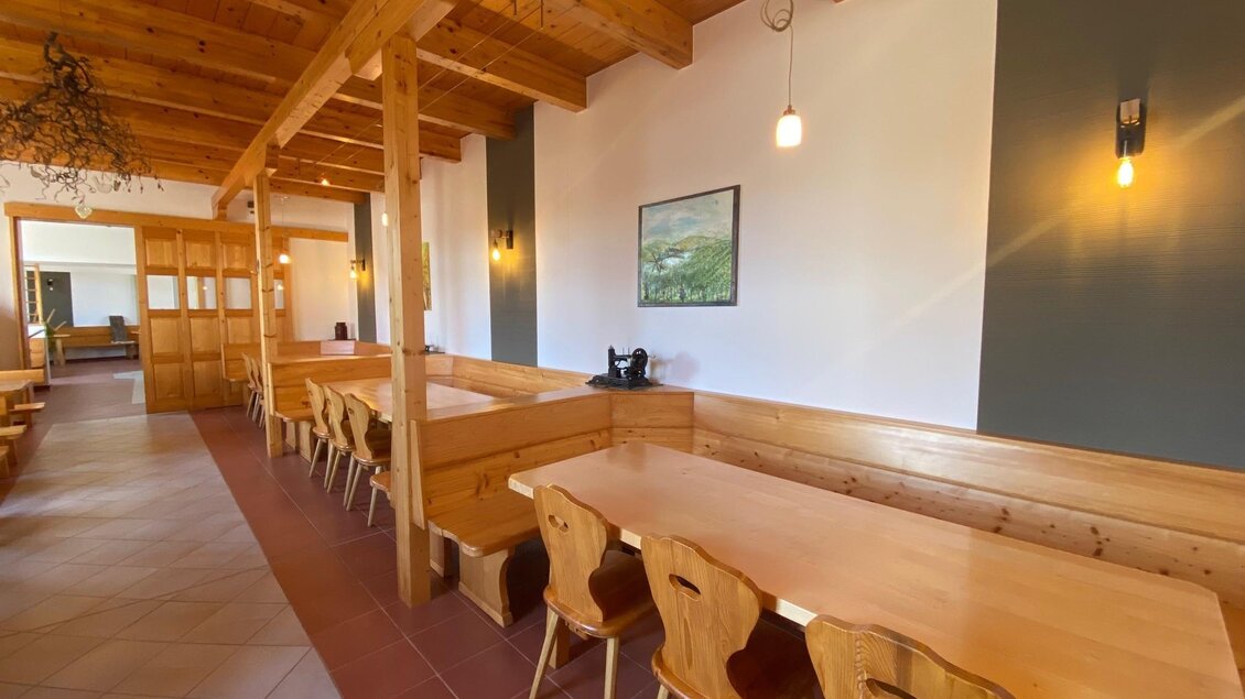 Ein gemütlicher Raum mit Holztischen und Stühlen. Die Wände sind in sanften Farben gehalten und es gibt angenehmes Licht. | © BS Weiß