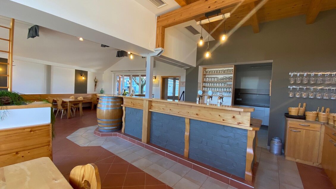 Ein modernes Restaurant mit Holzdekor und viel Tageslicht. Im Vordergrund befindet sich eine Bar mit einer Theke und einer gemütlichen Atmosphäre. | © BS Weiß