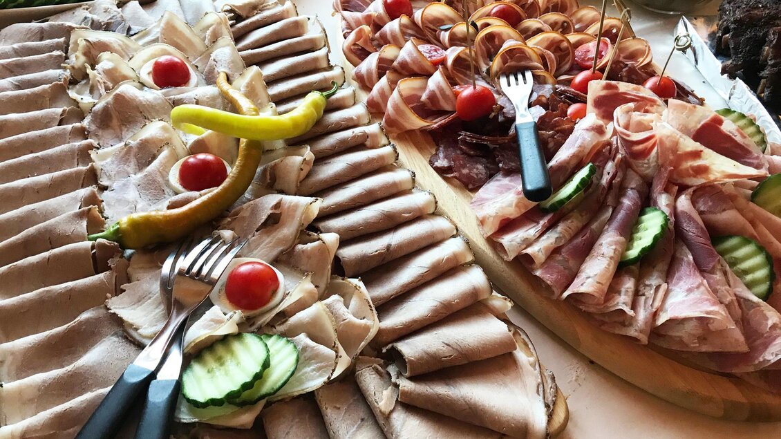 Eine Auswahl an Wurst- und Käseplatten mit Gurken und kleinen Tomaten. Die Teller sind dekorativ angerichtet und laden zum Probieren ein. | © Buschenschank Weiß