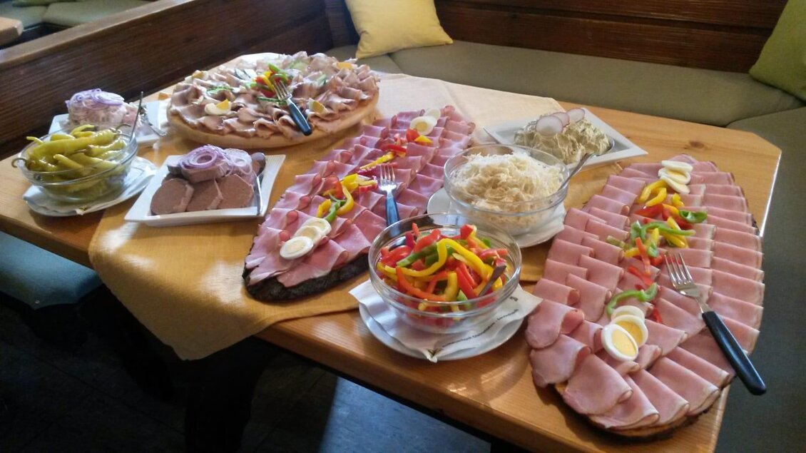 Ein reichhaltiges Buffet mit verschiedenen Käsesorten und Wurstplatten auf einem Holztisch. Dazu gibt es frisches Gemüse und Beilagen in Schalen. | © Andreas Wutti | Weingut Buschenschank Wutti