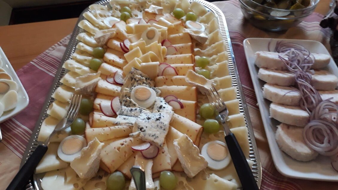 Ein großer Teller mit einer Vielzahl von Käsesorten, Trauben und Radieschen. Daneben befinden sich weitere Snacks auf einem Tisch. | © Andreas Wutti | Weingut Buschenschank Wutti