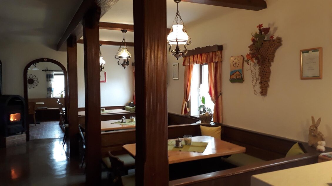 Ein gemütliches Restaurant mit Holztischen und Stühlen. Die Wände sind mit dekorativen Elementen und warmen Farben geschmückt. | © Andreas Wutti | Weingut Buschenschank Wutti