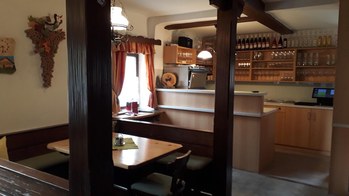 Ein gemütlicher Innenraum mit Holzdetails und einem Restaurantbereich. Die Bar ist gut ausgestattet, und es gibt Platz zum Essen und Entspannen. | © Andreas Wutti | Weingut Buschenschank Wutti