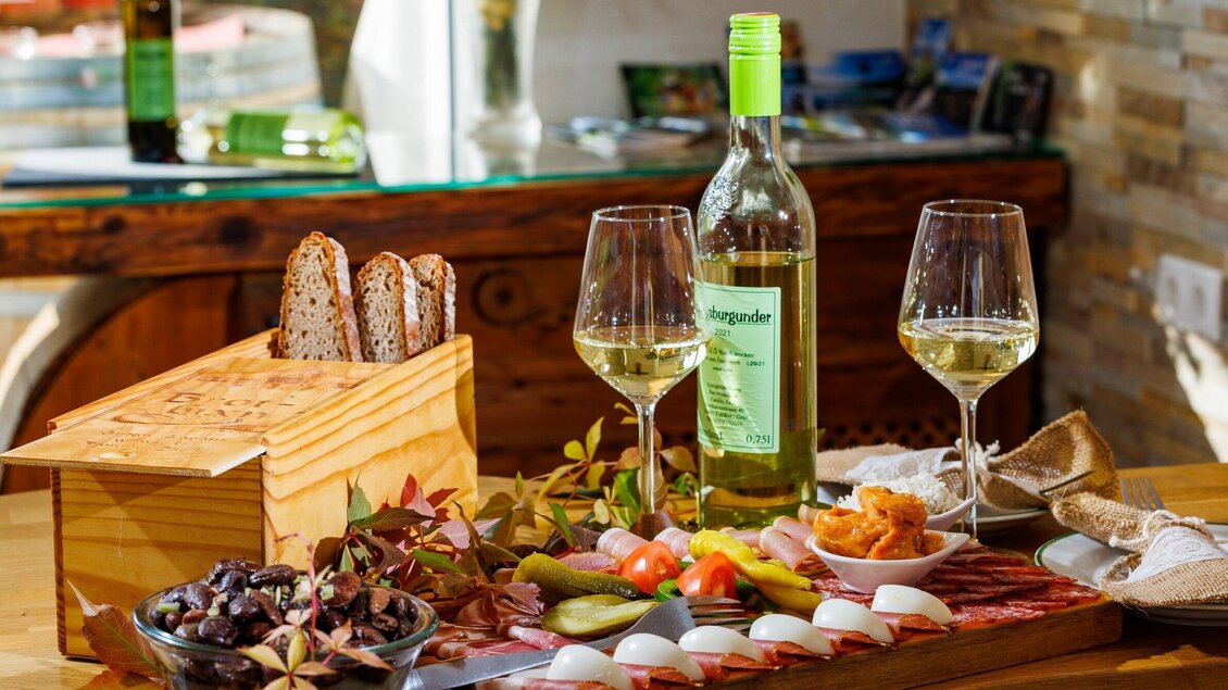 Ein Tisch gedeckt mit Wein, Gläsern und einer Auswahl an köstlichen Häppchen. Dazu Brot und frische Zutaten sind ansprechend arrangiert. | © TV Region Graz - Harry Schiffer