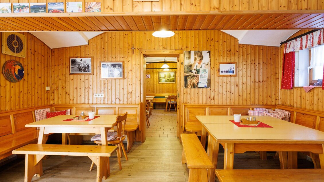 Ein gemütlicher Holzraum mit Tischen und Bänken. An den Wänden hängen Bilder, und die Atmosphäre wirkt einladend und rustikal. | © TV Region Graz - Harry Schiffer