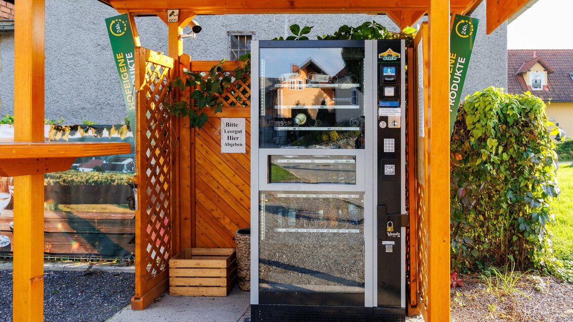 Ein Verkaufsautomat steht unter einem Holzüberstand. Die Umgebung ist gepflegt und von Pflanzen umgeben. | © TV Region Graz - Harry Schiffer