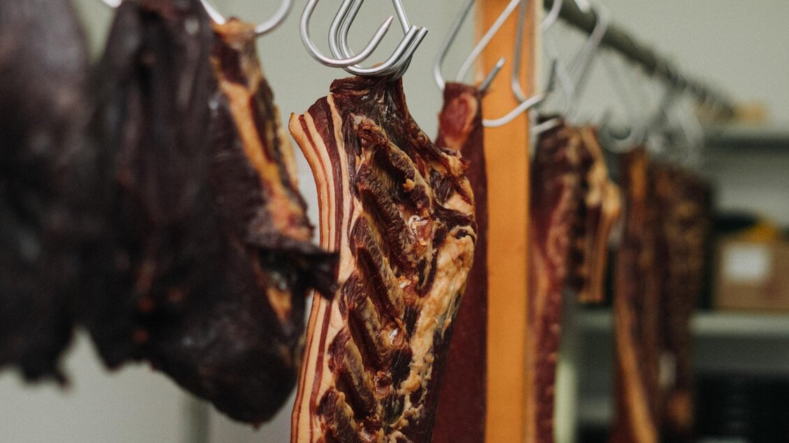 Eine Reihe von getrocknetem Fleisch hängt an Haken. Die Stücke sind in verschiedenen Farben und Texturen. | © Weingut & Buschenschank Zweytick | Fam. Zweytick