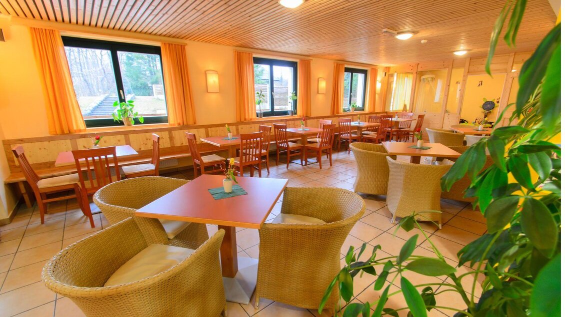 Ein schöner Spielplatz mit einem großen Trampolin und einer Rutsche. Im Hintergrund sind beeindruckende Berge und ein blauer Himmel zu sehen. | © Jufa_Hotel_Bad Aussee_(c) JUFA Hotels