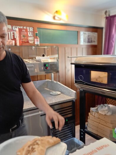 Ein Mann in einem Restaurant bereitet frisches Brot vor. Im Hintergrund sieht man einen modernen Ofen und verschiedene Kochutensilien. | © Thermen- & Vulkanland