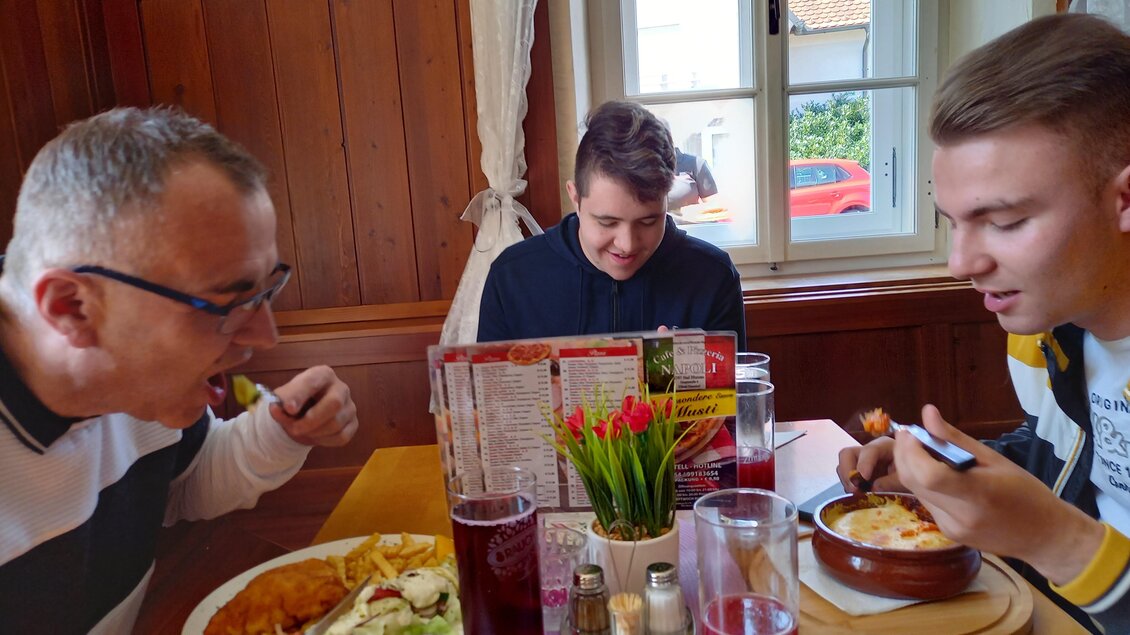 Drei Männer sitzen an einem Tisch in einem Restaurant und genießen ihr Essen. Auf dem Tisch stehen verschiedene Gerichte und Getränke. | © Thermen- & Vulkanland