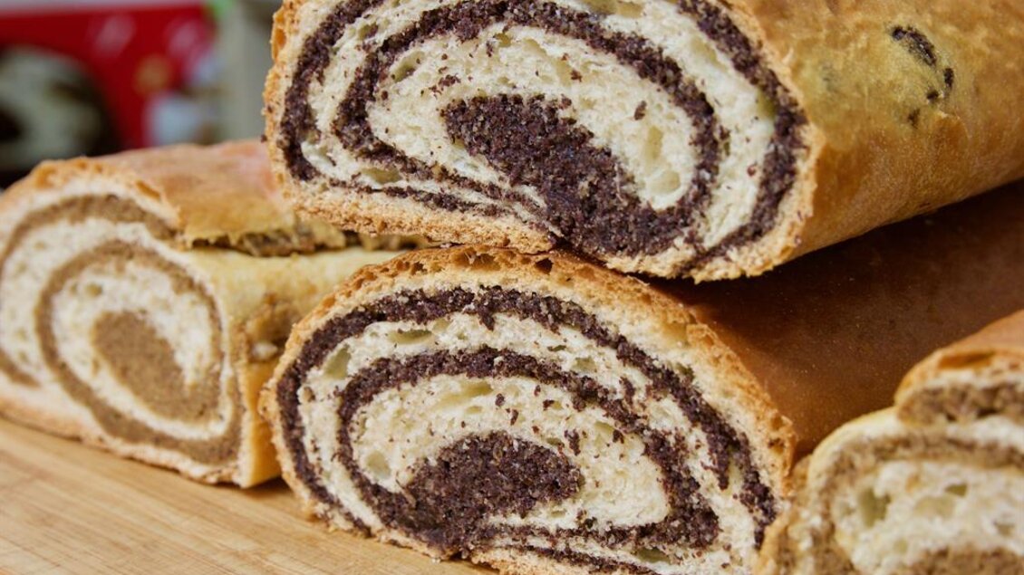 Ein geflochtener Hefekuchen mit einer Schicht aus dunkler und heller Füllung. Der Kuchen liegt auf einem Holzbrett und hat eine goldene Oberfläche. | © Rainer M. Fürstaller