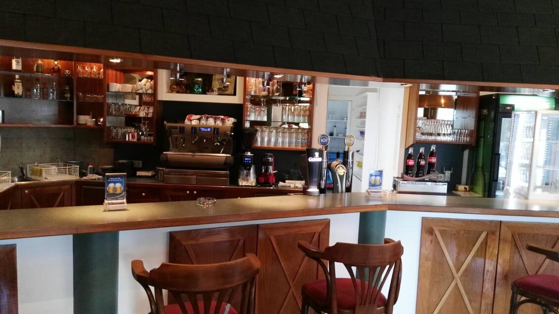 Ein gemütlicher Bartresen mit Holzstühlen und einer gut ausgestatteten Bar. Im Hintergrund sind Gläser und Getränke übersichtlich angeordnet. | © La Casa FB