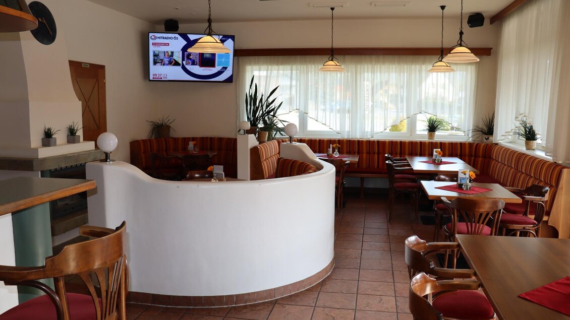 Ein gemütliches Restaurant mit Holzstühlen und einem hellen Innenraum. An der Wand hängt ein Fernseher, und große Fenster sorgen für viel Tageslicht. | © La Casa FB