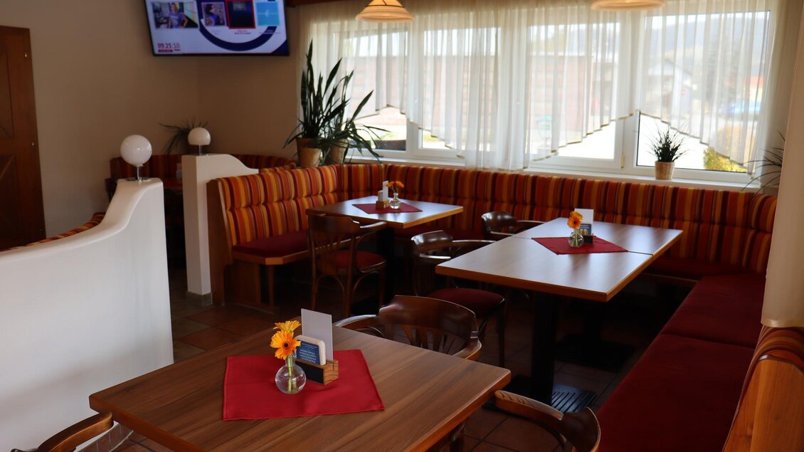 Ein gemütliches Restaurant mit Holztischen und bunten Sitzbänken. Große Fenster sorgen für ausreichend Tageslicht. | © La Casa FB