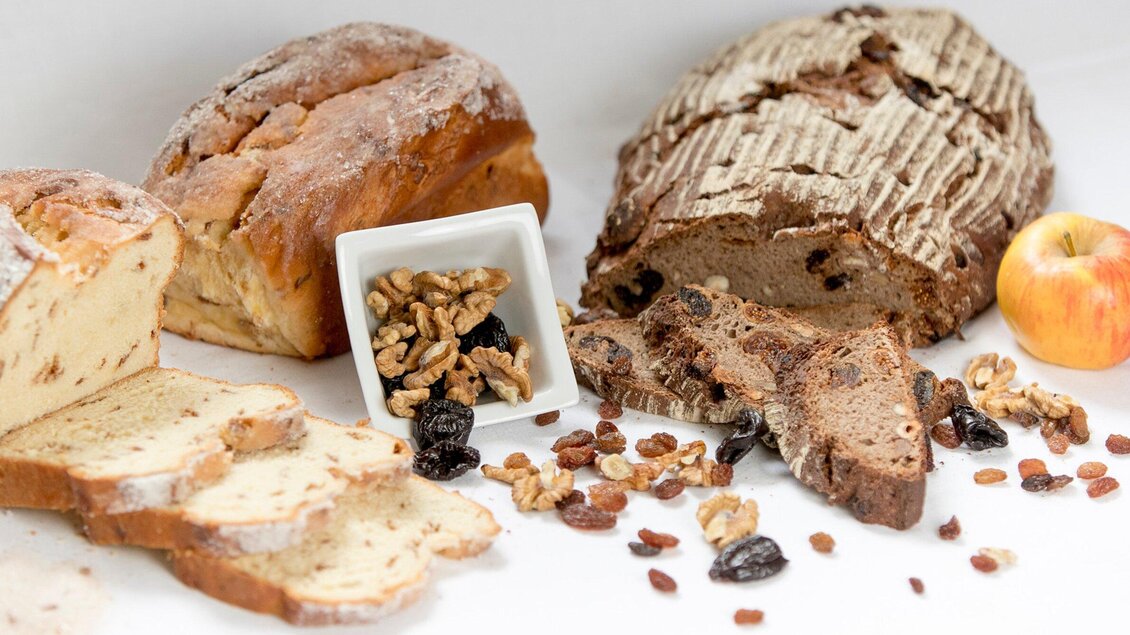 Ein schöner Tisch mit verschiedenen Brotsorten, Nüssen und Trockenfrüchten. Ein Stück Apfel rundet das Bild ab. | © TV Region Graz - Harry Schiffer