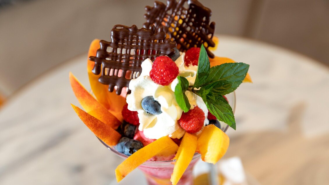 Ein leckeres Dessert mit frischen Früchten, Sahne und Schokoladendekor. Die bunten Zutaten verleihen dem Gericht eine ansprechende Optik. | © TV Region Graz - Harry Schiffer