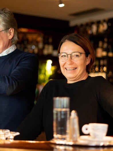 Ein gemütlicher Barbereich mit zwei Bartendern. Der Mann zapft Bier und die Frau lächelt freundlich. | © Cafe Beisl