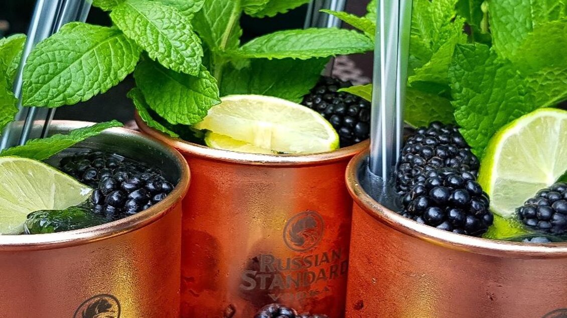 Erfrischende Cocktails in Kupferbechern mit Minze, Limette und Brombeeren. Einladend und perfekt für heiße Tage. | © Cafe Beisl