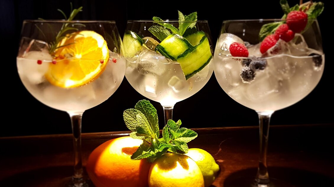 Drei Cocktails in großen Gläsern mit Eis und frischen Früchten. Äpfel, Zitronen und Minze liegen im Vordergrund. | © Cafe Beisl