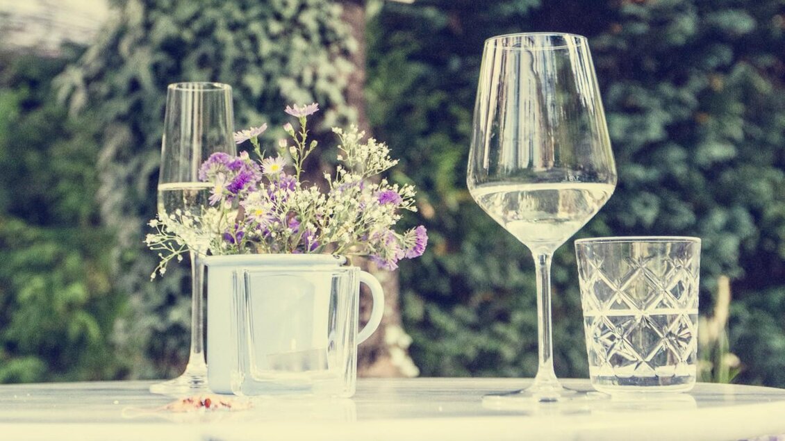 Ein schöner Tisch im Freien mit Gläsern und frischen Blumen. Im Hintergrund ist ein Schild mit Informationen zu sehen. | © Cafe Fotter