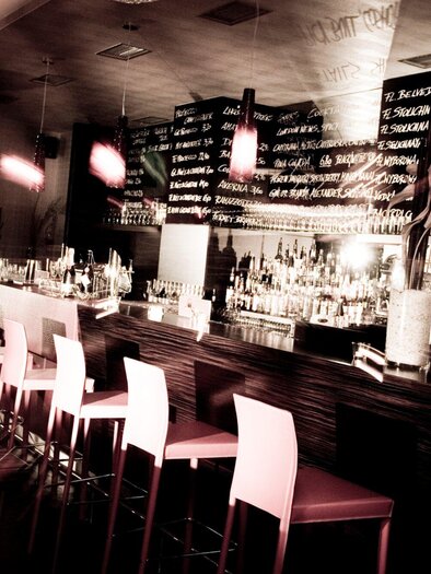 An elegant bar area with high chairs and a long counter. In the background, the drink menus are visible on the wall. | © Cafe Glockenspiel